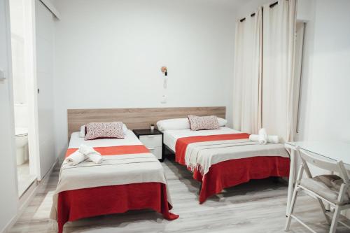 2 camas en una habitación con sábanas rojas y blancas en Hostal Ruta de Francia en Barcelona