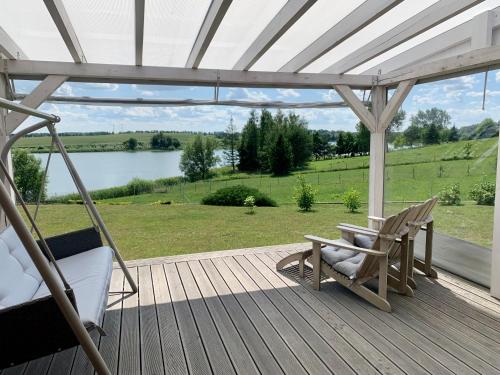 a porch with a swing and a chair and a lake at Dom nad jeziorem in Jeziorany