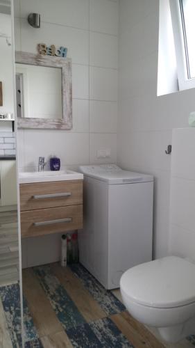 a white bathroom with a toilet and a sink at Całoroczne domki Morska Laguna in Kopalino