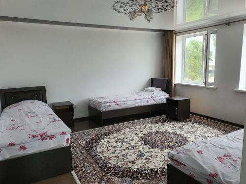 a room with two beds and a rug at MALIKA Guest House in Kochkorka