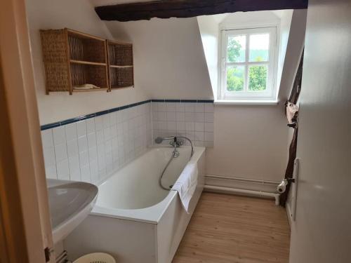 La salle de bains est pourvue d'une baignoire, d'un lavabo et d'une fenêtre. dans l'établissement La maison d'Hector, à Doudeville