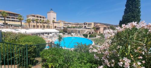 un complexe avec une piscine et quelques fleurs dans l'établissement Agay Cap Esterel Village Allée Fleurs - F2 Clim vue golf et mer - Grande terrasse plein sud, à Agay