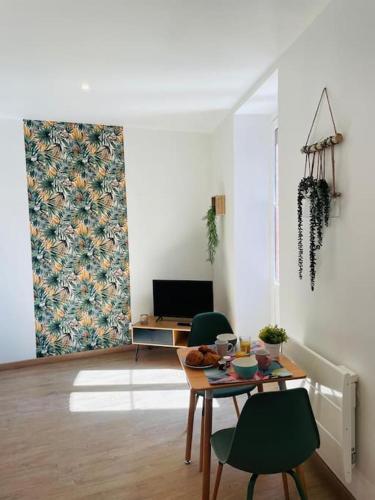 a living room with a table and chairs and a tv at L’échappée verte in Caussade