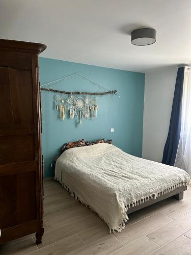 une chambre avec un lit avec un mur bleu dans l'établissement Maison Thany 2, à Vals-les-Bains