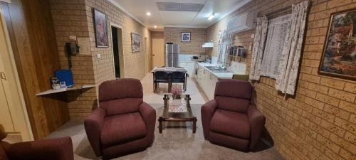 Habitación con 2 sillas y cocina. en Lone Pine Motel, en Corowa