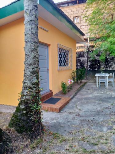 a yellow house with a blue door and a tree at La Chambre de Cosy in Libreville