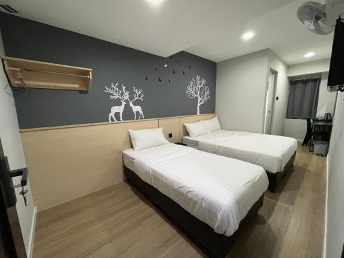 2 camas en una habitación con calcomanías de ciervo en la pared en OU INN Cameron Highlands ,Ferm Nyonya Restaurant en Tanah Rata