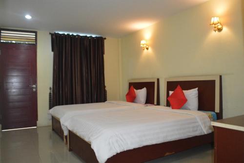 a bedroom with a large bed with red pillows at Hotel Toba Shanda By Helocus in Parapat