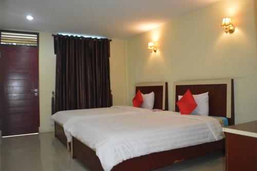 um quarto com uma cama grande e almofadas vermelhas em Hotel Toba Shanda By Helocus em Parapat