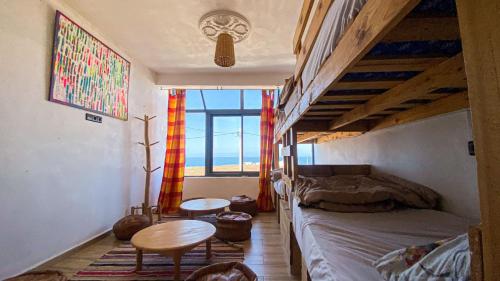 - une chambre avec des lits superposés et une table dans l'établissement EL Faro Surfstay, à Tamri