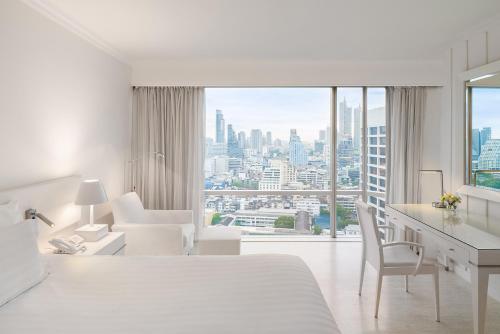 曼谷Pullman Bangkok Hotel G的白色的酒店客房,设有书桌和大窗户