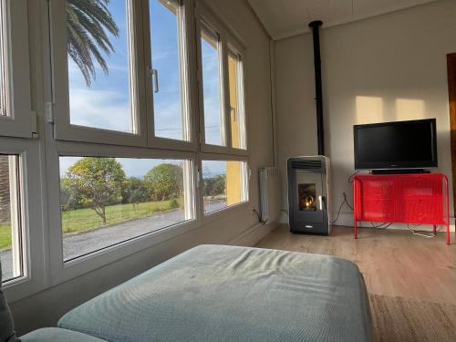 um quarto com uma cama, uma televisão e janelas em Villa La Palmera y El Mar em Naveces
