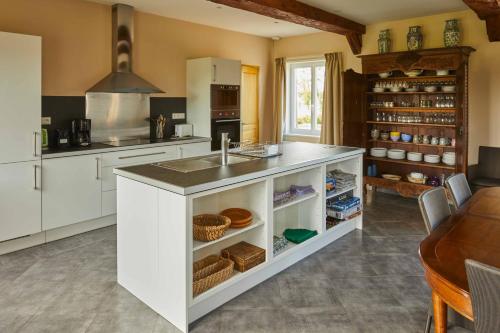 eine Küche mit einer weißen Insel und einem Waschbecken in der Unterkunft La Maison de Charlotte in Doudeville