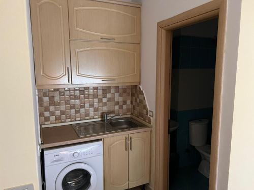 een kleine keuken met een wastafel en een wasmachine bij Rexhina Apartments in Durrës