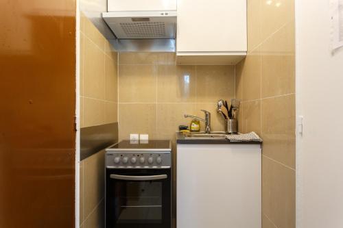 uma pequena cozinha com um fogão e um lavatório em Jean Jaurès chambre 1ére étage em Aubervilliers