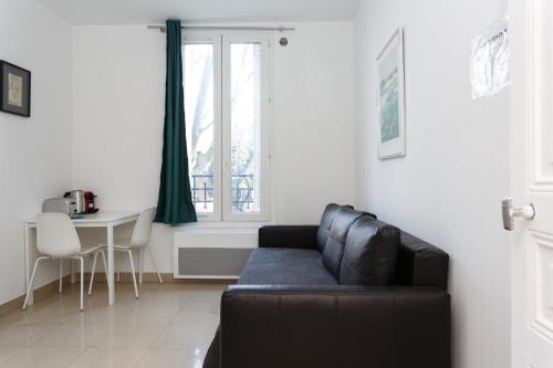 un soggiorno con divano nero e tavolo di Jean Jaurès chambre 1ére étage ad Aubervilliers