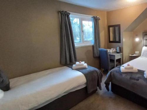 a hotel room with two beds and a window at Highland Bridge Hotel in Spean Bridge