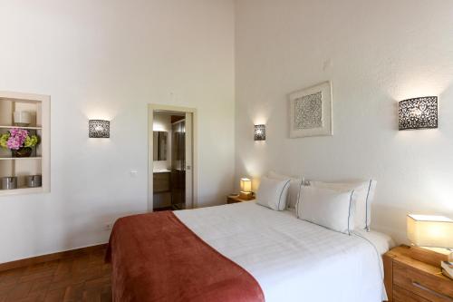 a bedroom with a large white bed and lights on the wall at Pedras Da Rainha in Cabanas de Tavira