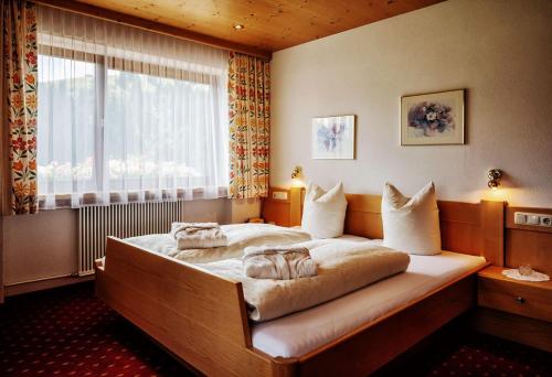 sypialnia z dużym łóżkiem i oknem w obiekcie Pension Uga w mieście Damüls