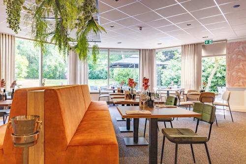 un restaurante con mesas, sillas y ventanas en Fletcher Hotel-Restaurant De Scheperskamp, en Lochem