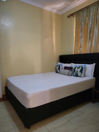 - une chambre dotée d'un grand lit avec des draps et des oreillers blancs dans l'établissement G&G Westindies Executive One Bedroom, à Eldoret