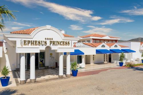 um edifício branco com guarda-chuvas azuis em frente em Labranda Ephesus Princess - All Inclusive em Kusadasi