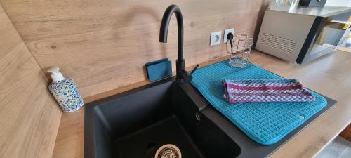 a kitchen counter with a sink with a blue tray at Tiny house cosy proche Disney in Bannost