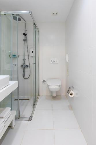 a white bathroom with a shower and a toilet at Labranda TMT Bodrum in Bodrum City