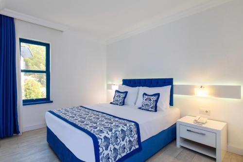 a bedroom with a blue and white bed and a window at Labranda Ephesus Princess - All Inclusive in Kusadası