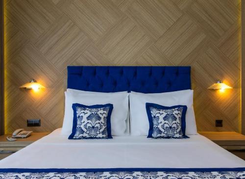 a bedroom with a bed with blue and white pillows at Labranda Ephesus Princess - All Inclusive in Kusadası