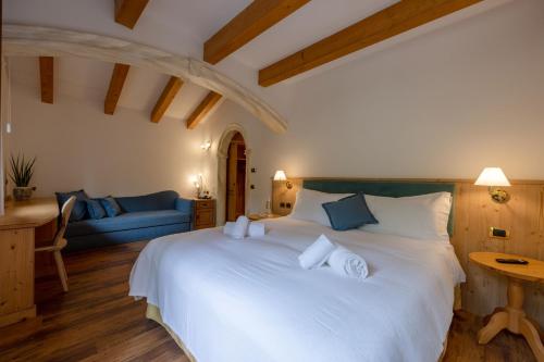 a bedroom with a large white bed with a blue couch at Hotel Stalon Alpine Chic in San Martino di Castrozza