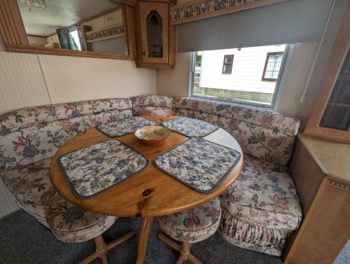 a table and a couch in a tiny house at 30 Glenfinart Caravan Park in Dunoon