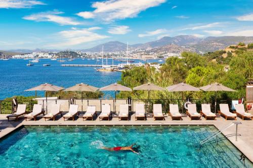 a person swimming in a pool with chairs and umbrellas at Senses Hotel - Adults Only in Bodrum City