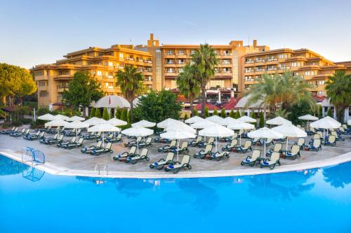 a hotel with a pool and chairs and umbrellas at Asteria Family Resort Belek in Belek