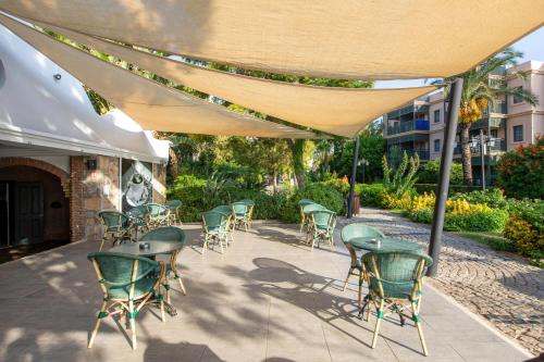 a patio with chairs and tables under a canopy at Kairaba Bodrum Imperial in Akyarlar