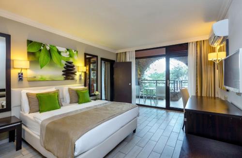 Marmaris Bay Resort - Adults Only في مرماريس: غرفة نوم بسرير ومكتب وشرفة