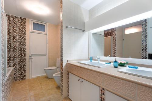 W łazience znajduje się umywalka, toaleta i lustro. w obiekcie Maravilla Over the Ocean w mieście Costa Del Silencio