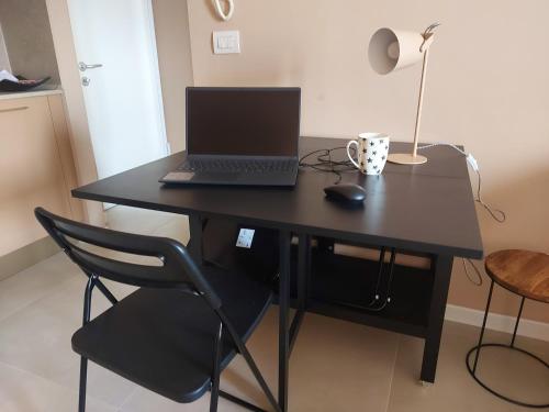 a laptop computer sitting on a black desk with a chair at A spasso in Ventimiglia