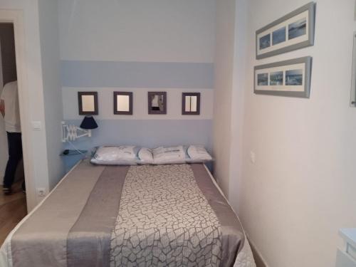 uma cama num quarto branco com fotografias na parede em Mogro con vistas al mar y Garaje! em Mogro