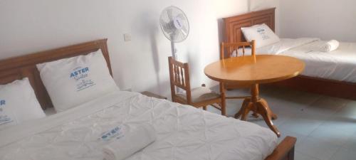 a bedroom with two beds and a table and a desk at Aster Suites Kisumu in Awasi