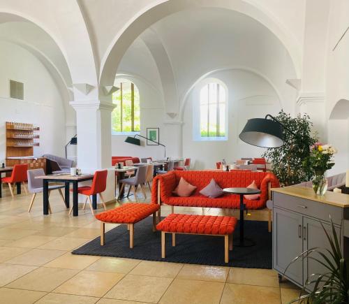 un vestíbulo con muebles rojos, mesas y sillas en Hotel Klostergasthof, en Thierhaupten
