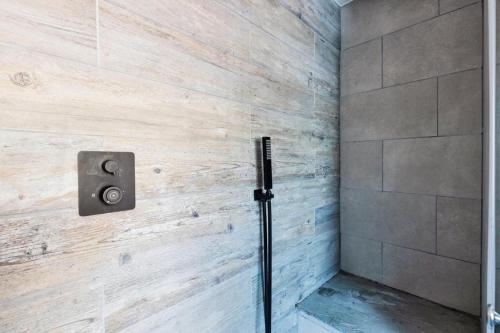 y baño con ducha y pared de madera. en Stunning Refurbished Apartment in Central Cheltenham inc. Parking, en Cheltenham