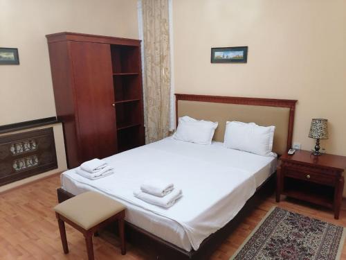 um quarto com uma cama com lençóis brancos e uma cadeira em Sarbon Plaza Hotel em Bukhara