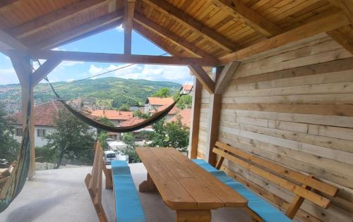 eine Holzterrasse mit einer Hängematte und einer Holzbank in der Unterkunft Apartments Amina Sarajevo in Sarajevo
