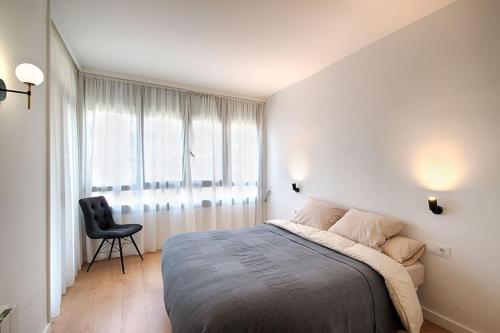 a bedroom with a bed and a chair and a window at Apartament Girona Center in Girona