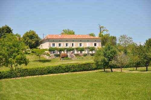 una casa grande en un campo verde con árboles en Domaine de Puyrousse, en Ribérac