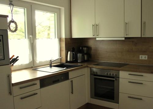 a kitchen with white cabinets and a sink and a window at Ferienhaus Lorenz` Gartentraum - Emsland in Dörpen