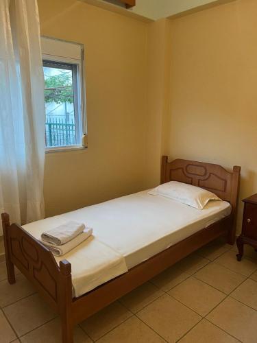 a bedroom with a bed with white sheets and a window at Eden Apartments in Qeparo