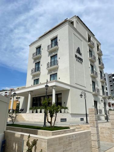 un edificio blanco con un árbol delante en Seaside Hotel, en Vlorë