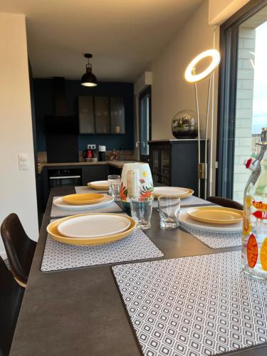 une cuisine avec une table avec des assiettes dessus dans l'établissement A 10 mn de Disney Land Paris Appartement neuf, à Bussy-Saint-Georges